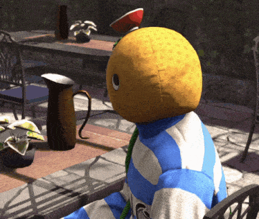 a person in a blue and white striped shirt has a stuffed lemon on their head