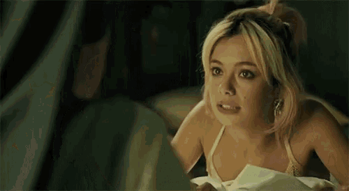 a woman in a bikini is sitting on a bed talking to another woman .