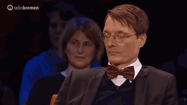 a man in a suit and bow tie is applauding in front of a radio bremen logo