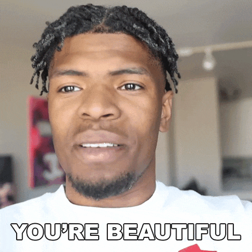 a man with dreadlocks and the words you 're beautiful on his shirt