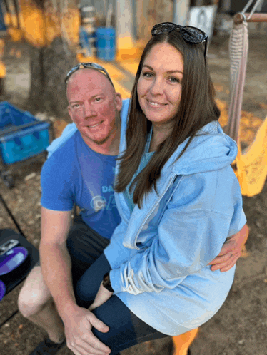 a man and woman are posing for a picture and the man is wearing a blue shirt that says da