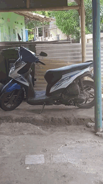 a blue and white honda beat scooter is parked on a sidewalk