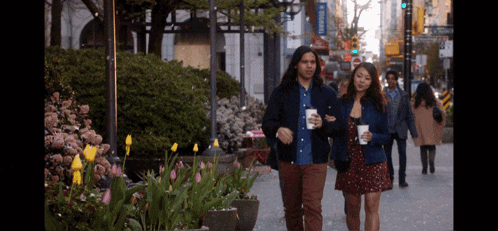 a man and a woman walking down a sidewalk with a sign that says ' abercrombie ' on it