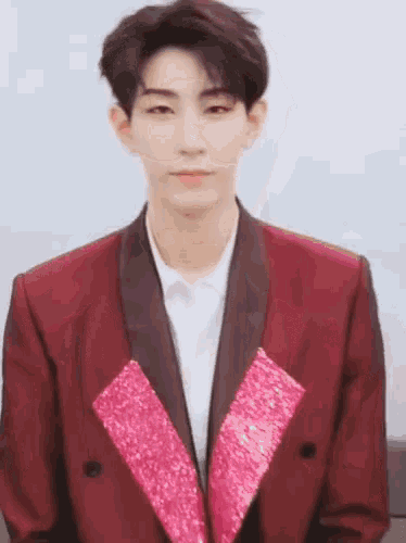a young man is wearing a red suit with a pink collar