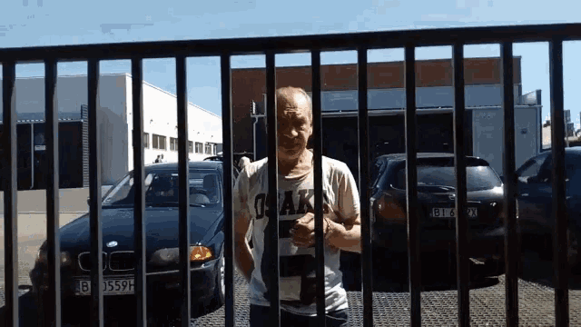 a man wearing a shirt that says osaka is standing behind bars