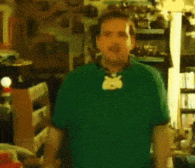 a man wearing a green shirt with a cat necklace around his neck .