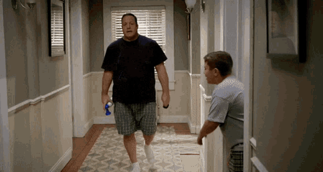 a man walking down a hallway holding a bottle of water