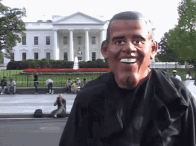 a man wearing a barack obama mask is smiling in front of the white house