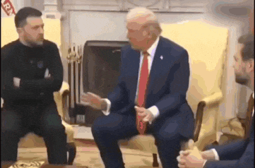 a man in a suit and tie is sitting in a chair talking to two men .