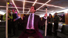 a man in a suit and tie is standing on a pole in a room
