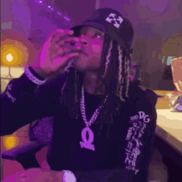 a man with dreadlocks is wearing a black shirt with the letter q on it