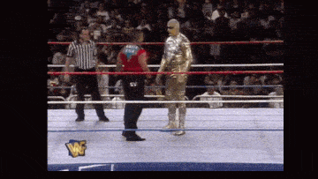a wrestling ring with a wrestler in a gold suit