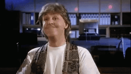 a man wearing a vest and a white shirt is making a face .