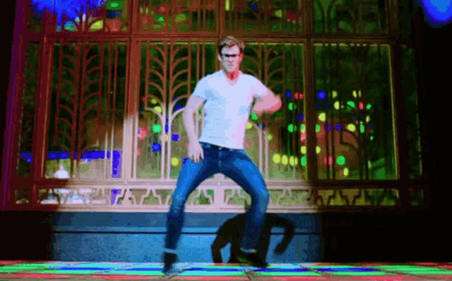 a man in a white shirt and jeans is dancing in front of a stained glass window