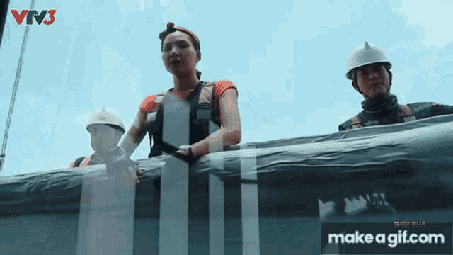 a woman stands next to a man wearing hard hats in front of a screen that says make a gif.com on it