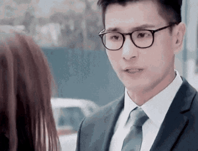 a man in a suit and tie is looking at a woman in a car .