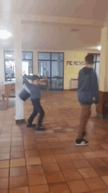 two boys are playing in a hallway with a sign that says mc resis on it