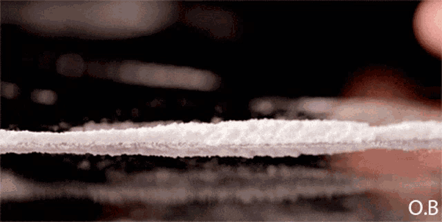 a close up of a line of cocaine with the letters o.b. on the bottom right