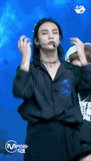 a man in a black shirt is dancing on a stage in front of a blue background that says mpd