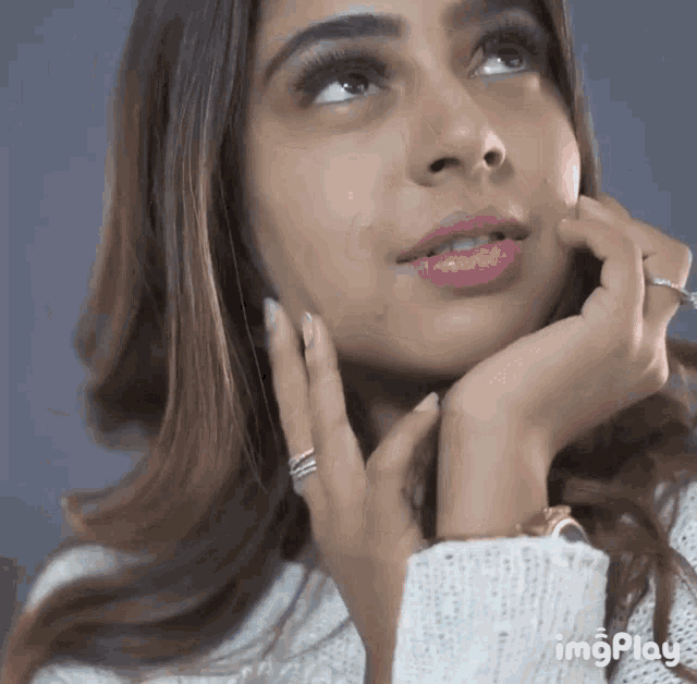 a close up of a woman 's face with a ring on her finger .