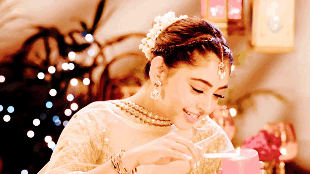 a woman with a flower in her hair is smiling while holding a candle