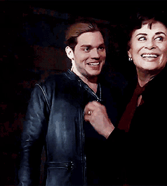 a man in a leather jacket is smiling next to a woman