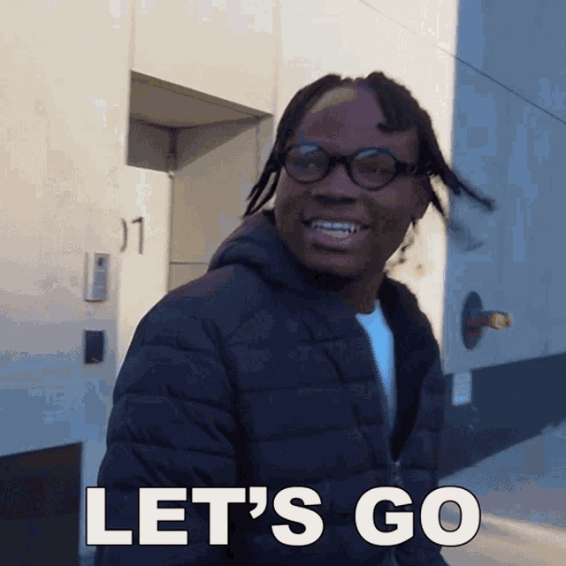a man wearing glasses and a jacket says " let 's go "