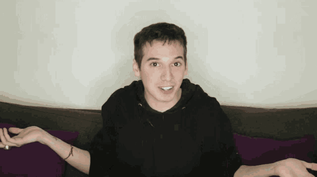a young man is sitting on a couch with his hands outstretched