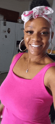 a woman wearing a pink tank top and hoop earrings is smiling for the camera