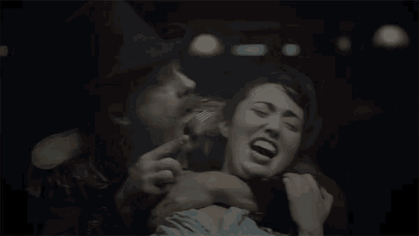 a man in a top hat is licking a woman 's face with a fork