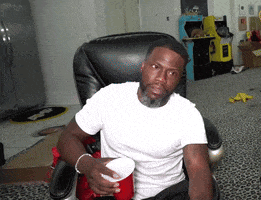 a man in a white shirt is sitting in a chair with a red cup in his hand