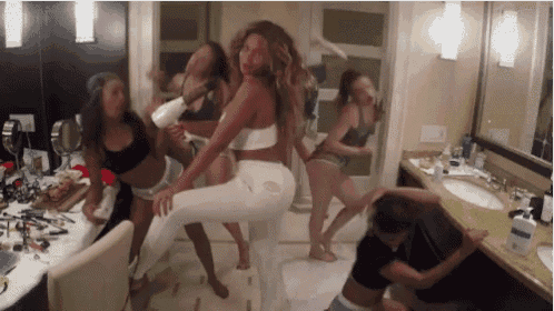 a group of women are dancing in a bathroom with a woman holding a hair dryer