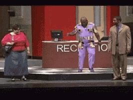 a man in purple pants stands in front of a reception desk