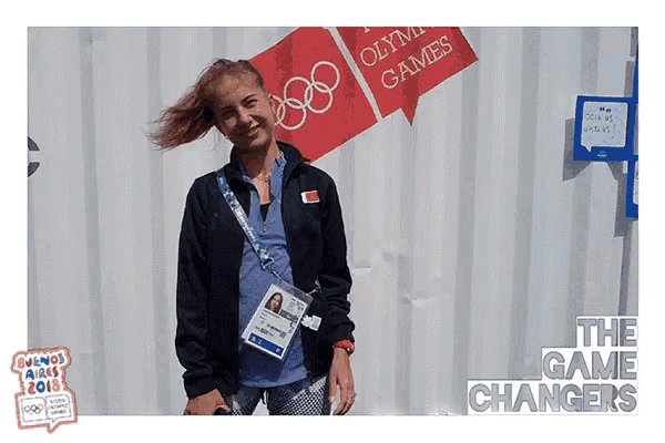 a woman stands in front of a sign that says " olympic games "