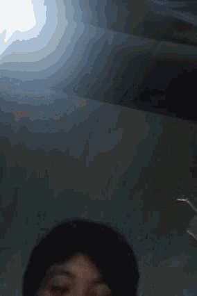 a person 's head is visible in a dark room with a light shining through the ceiling