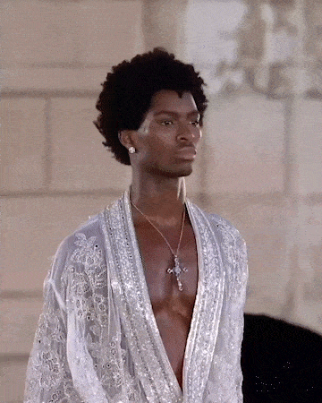a man is wearing a white robe and a cross necklace