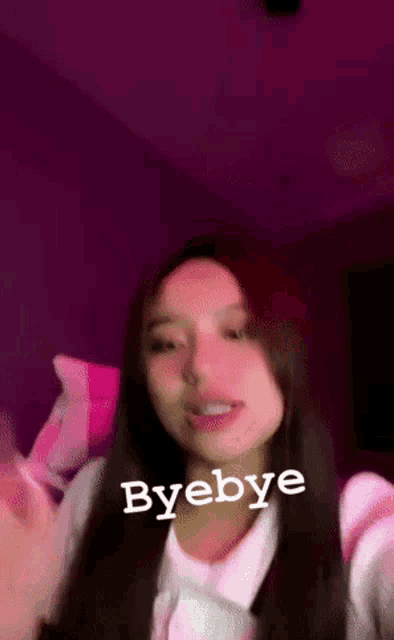 a woman with long hair is standing in front of a purple light and says byebye .