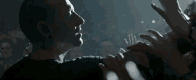 a man is clapping his hands in a crowd of people at a concert .