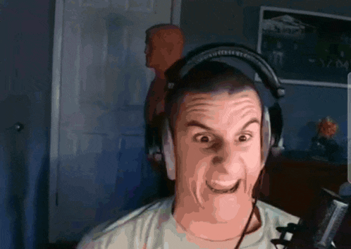 a man wearing headphones makes a funny face in front of a microphone