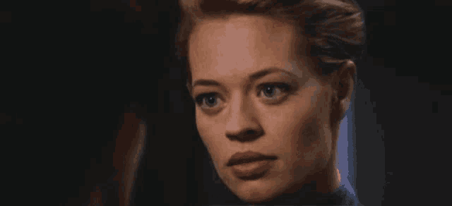 a close up of a woman 's face with a man behind her