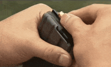 a person is putting a bullet into a magazine .
