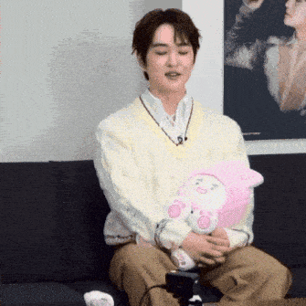a man is sitting on a couch holding a stuffed animal