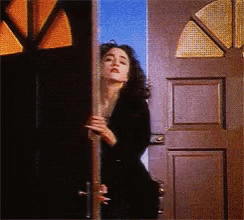 a woman is standing in a doorway with a cigarette in her hand