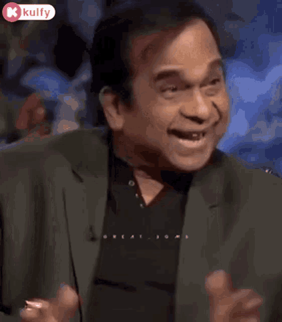 a man in a suit and black shirt is making a funny face while talking on a television show .