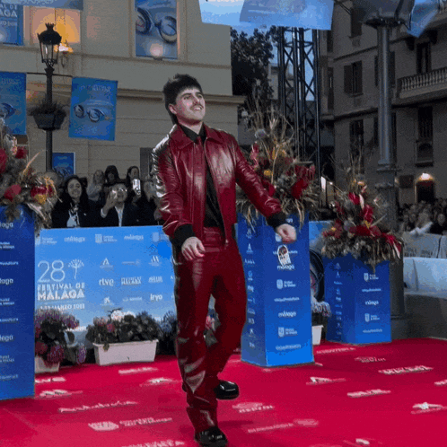 a man in a red leather jacket walks on a red carpet at the 28th festival de malaga