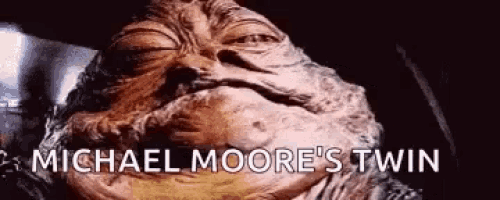 a close up of jabba the hutt 's face with the words `` michael moore 's twin '' written below it .