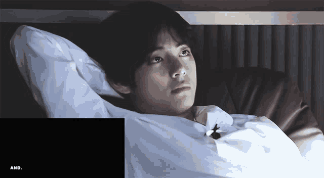 a man in a white shirt is laying in a bed