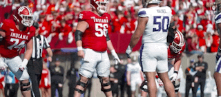 a group of football players are standing on a field and one of them is wearing a number 50 jersey .