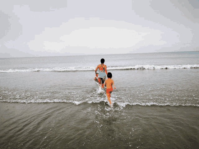 a woman and a boy are walking out of the ocean