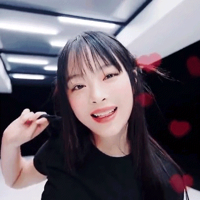 a close up of a woman 's face with hearts in the background . she is wearing a black shirt and smiling .